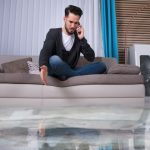 A man sitting on top of a couch talking on the phone.