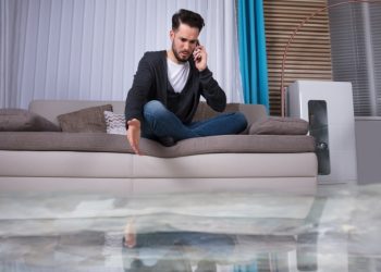 A man sitting on top of a couch talking on the phone.