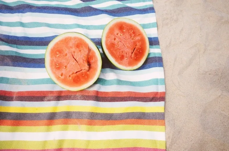 Two halves of a watermelon on top of a towel.