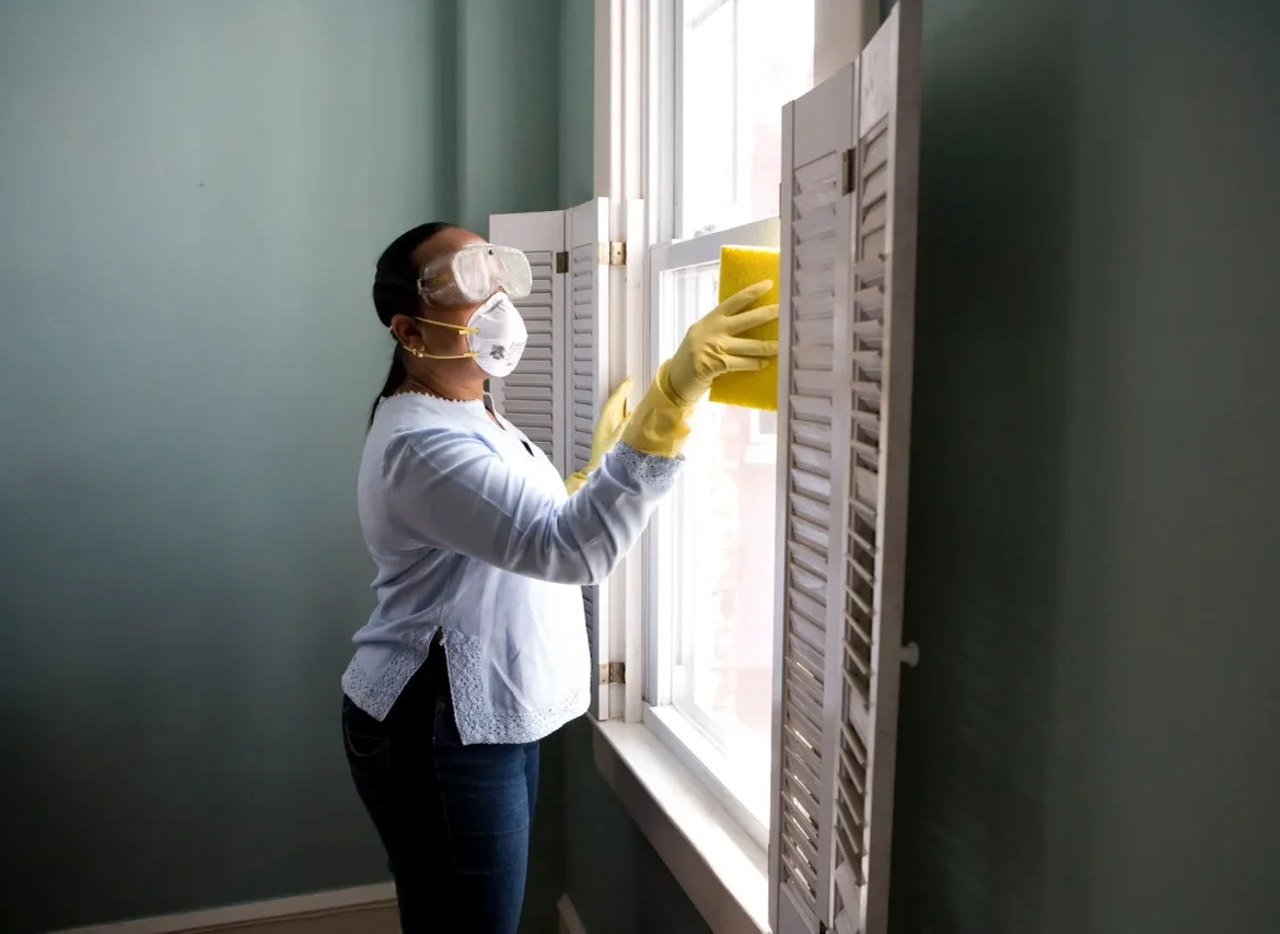 A woman in yellow gloves cleaning the window.