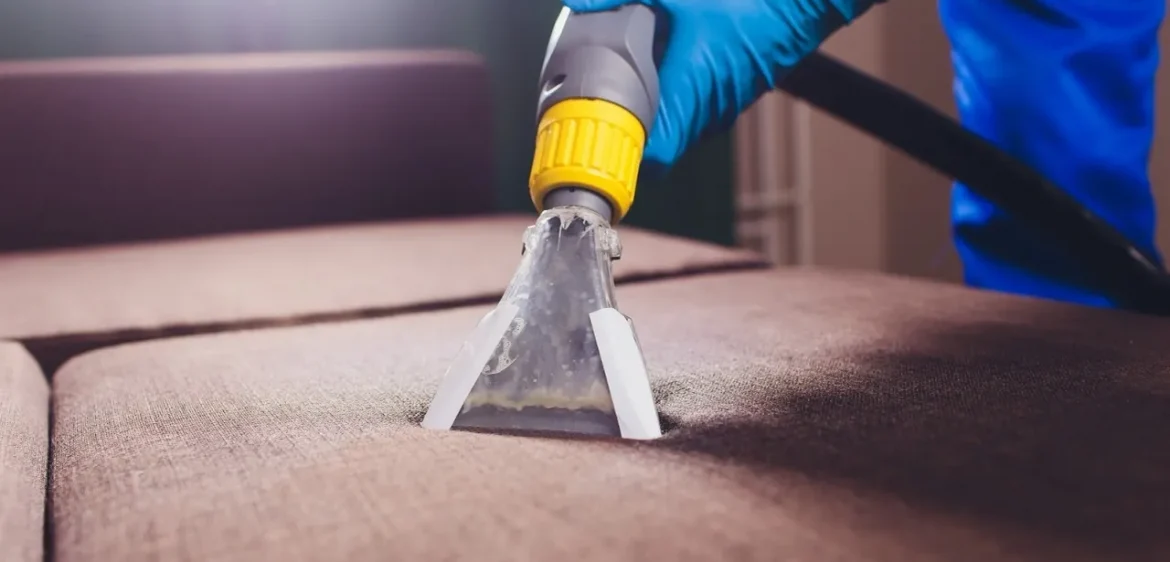A person in blue gloves using an electric tool to remove dirt from the floor.
