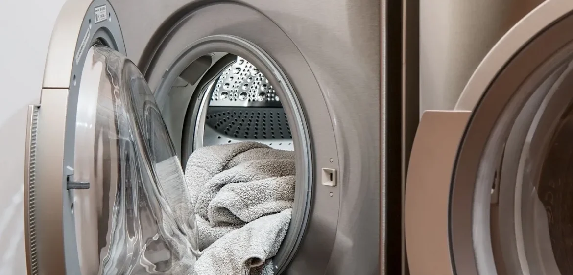 A silver washing machine with some towels on it