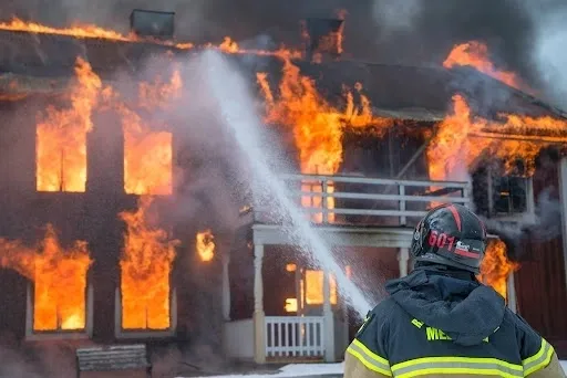 A fireman spraying water on a fire that is burning.