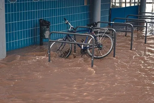 A bicycle is sitting in the water near a parking meter.