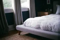 A bed with white sheets and pillows on it.