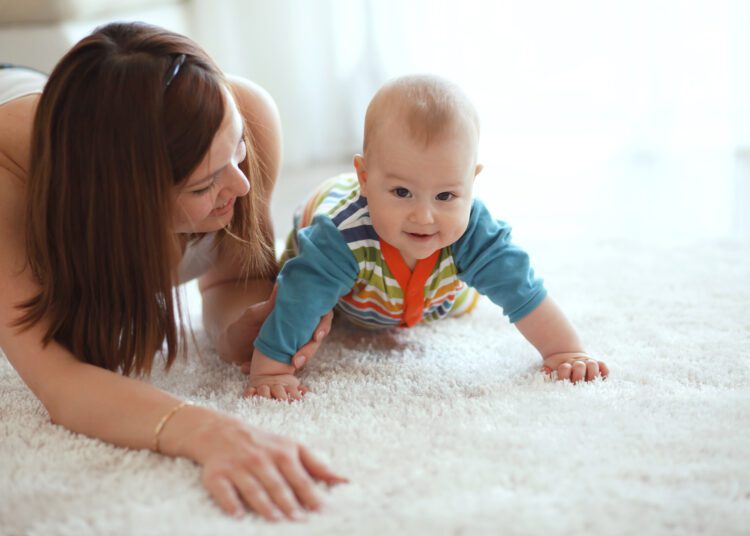 A woman is playing with her baby on the floor