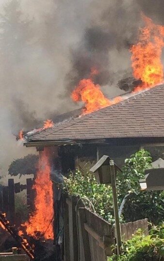 A house that is on fire with smoke coming out of the roof.