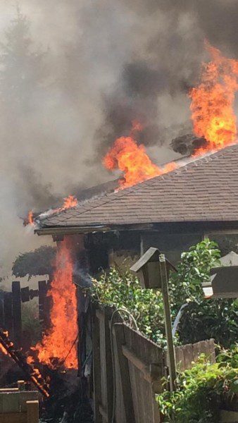 A house that is on fire with smoke coming out of the roof.